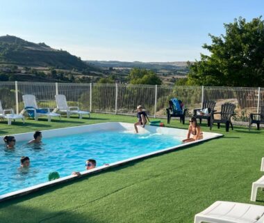 Dans l'Aveyron piscine extérieure avec baigneurs et chaises longues au camping Val St Georges