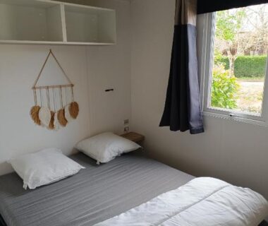 Chambre avec lit double et fenêtre donnant sur jardin au camping Vacances dans les Landes