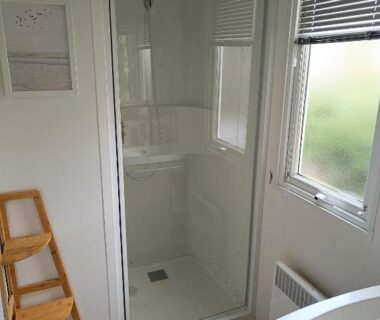 Salle de bain avec cabine de douche et fenêtre au camping Vacances dans les Landes