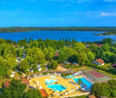Piscine extérieure et lac en arrière-plan au camping Vacances dans les Landes