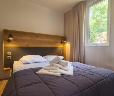 Chambre avec lit double et serviettes dans le mobil-home Camp'in Pirellu