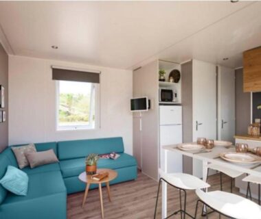 Séjour lumineux avec canapé turquoise et kitchenette dans un mobil-home du Camp'in Pirellu