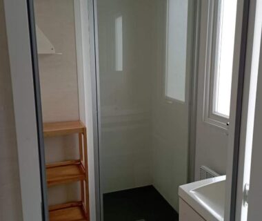 Salle d'eau avec cabine de douche lavabo étagère et fenêtre dans l'hébergement Val Océan-bord de plage
