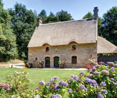 Maison en chaume et hortensias dans le jardin au camping Vallée de Pratmeur