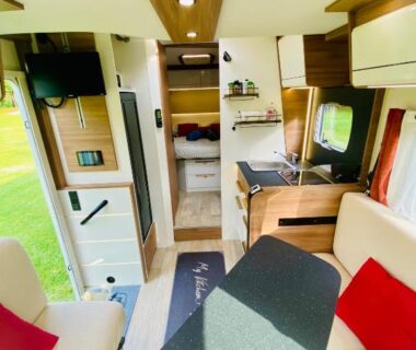 Intérieur de van aménagé avec salon table kitchenette et coin nuit dans le Vanlodge