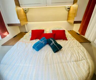 Chambre avec lit rond coussins rouges et serviettes bleues dans le Vanlodge