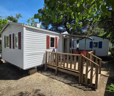 Emplacement avec mobilhome et terrasse sous les arbres au Camping Les Salisses Vias Plage
