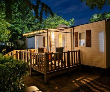 Terrasse en bois éclairée la nuit devant un mobilhome au Vias Plage Camping Les Salisses Mobilhome