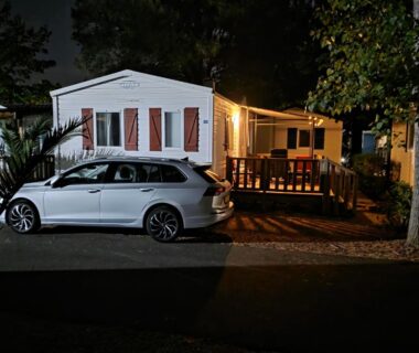 Allée et terrasse éclairées avec voiture garée au mobilhome du Camping Les Salisses Vias Plage