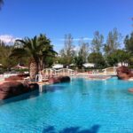 Piscine extérieure avec ponts palmiers et transats au Vias-Plage Camping Les Salisses Quality Holidays
