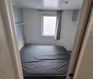 Chambre avec lit étagères et fenêtre dans le mobil home La Carabasse