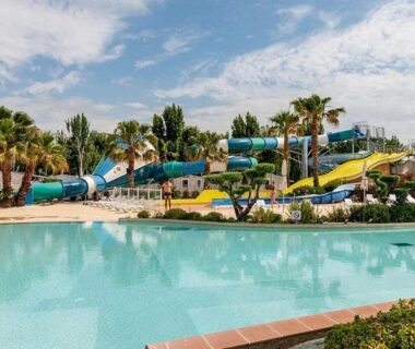 Piscine avec toboggans et palmiers au mobil home MER & SOLEIL du camping La Carabasse