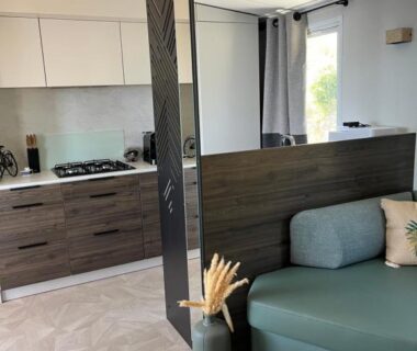 Salon et kitchenette avec canapé et cloison décorative dans le mobil-home du View and Dream