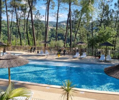 Piscine et parasols au milieu des pins au Village de Chalets