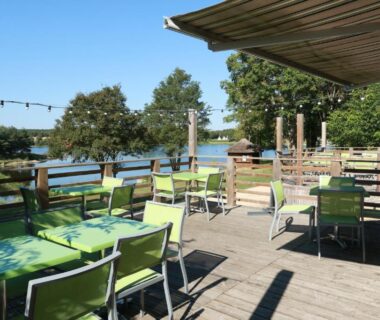 Terrasse au bord de l'eau avec tables et chaises du Village loisirs de Goule
