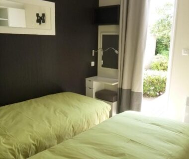 Chambre avec deux lits et porte-fenêtre vers l'extérieur au Village vacances & camping de Gruissan