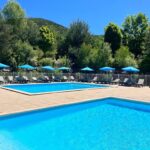 Piscines extérieures avec parasols au camping La Pierre de l'Aigle