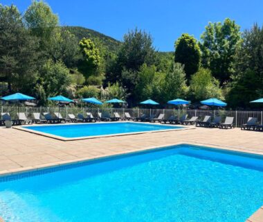 Piscines extérieures avec parasols au camping La Pierre de l'Aigle