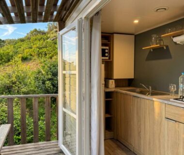 Balcon en bois donnant sur la végétation avec kitchenette ouverte dans le logement Vista Mare