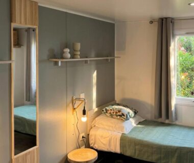 Chambre avec lit simple et fenêtre donnant sur la végétation au camping Vista Mare Cap Corse