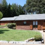 Pelouse et chalets en bois avec table de jardin au Volcans Vacances Les Chalets Du Lac