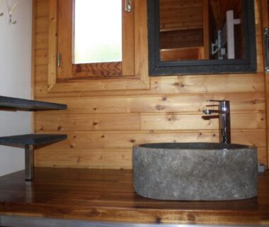 Salle de bains en bois avec vasque en pierre au Volcans Vacances Les Chalets Du Lac