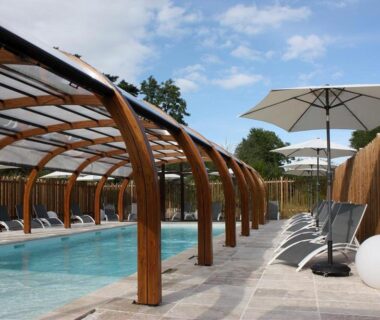 Piscine couverte avec transats et parasols au camping Volcans Vacances Les Chalets Du Lac