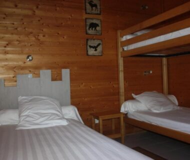 Chambre en bois avec lits superposés et lit simple au Volcans Vacances Les Chalets Du Lac