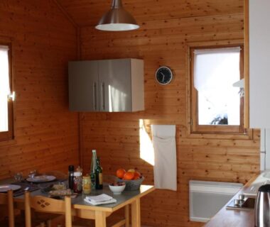 Intérieur de chalet avec cuisine et table en bois dans le Volcans Vacances Les Chalets Du Lac