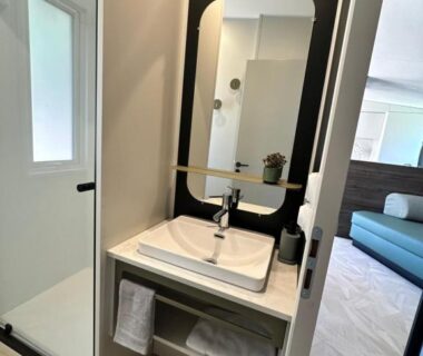 Salle de bain avec lavabo miroir et douche au camping Voltaire