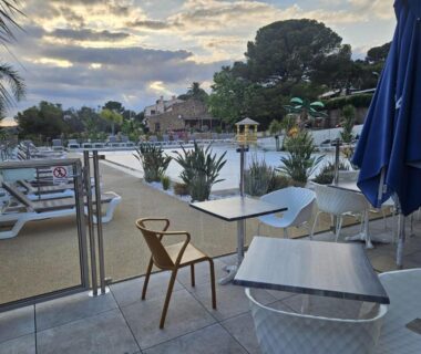 Terrasse avec tables et piscine du camping Voltaire