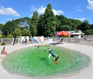 Bassin circulaire vert avec enfant plongeant et parasols au ZEcamping 3 étoiles 4km plage piscine sauna dog friendly salle fitness