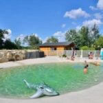 Piscine extérieure en lagon avec gonflable et baigneurs au ZEcamping 3 étoiles