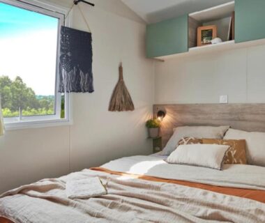 Intérieur de chambre avec lit et fenêtre donnant sur le jardin au ZEcamping 3 étoiles