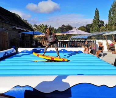 Espace extérieur avec simulateur de surf gonflable et spectateurs au ZEcamping 3 étoiles