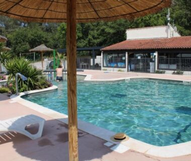 Bord de piscine avec parasols et transats au ZEcamping 3 étoiles