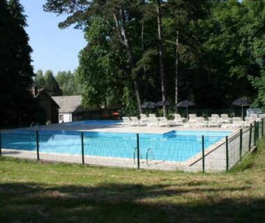 Piscine extérieure avec chaises longues et clôture au ZEcamping 3 étoiles animations piscine chauffée