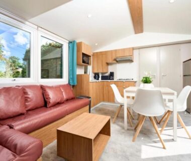 Intérieur du mobil-home avec canapé rouge et kitchenette dans le ZEcamping 3 étoiles