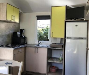Kitchenette avec réfrigérateur, évier, plaque de cuisson et TV dans le mobil home ZEcamping 3 étoiles animaux acceptés équitation pataugeoire