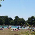 Plage de lac et pelouse avec baigneurs au ZEcamping 3 étoiles animaux acceptés sauna piscine couverte