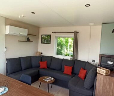Coin salon avec canapé gris et coussins rouges dans le mobile home ZEcamping 3 étoiles animaux acceptés sauna piscine couverte