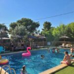 Piscine extérieure avec baigneurs parasols et bouée flamant rose au ZEcamping 3 étoiles