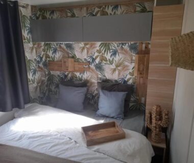 Chambre avec lit coussins et papier peint tropical au ZEcamping 3 étoiles avec piscine chauffée bar et restaurant