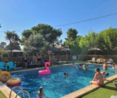 Piscine extérieure avec baigneurs parasols et bouée flamant rose au ZEcamping 3 étoiles
