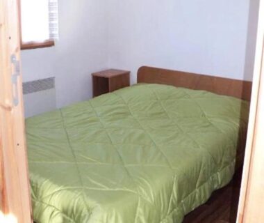 Chambre avec lit et couette verte dans le ZEcamping 3 étoiles avec piscine et pataugeoire