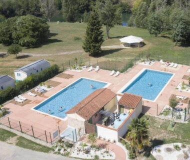 Espace piscines extérieures avec chaises longues au ZEcamping 3 étoiles chiens acceptés piscine en bord de rivière avec Canoë
