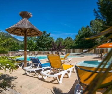 Bord de piscine avec transats et parasol en paille au ZEcamping 3 étoiles club enfant équitation piscine chauffée