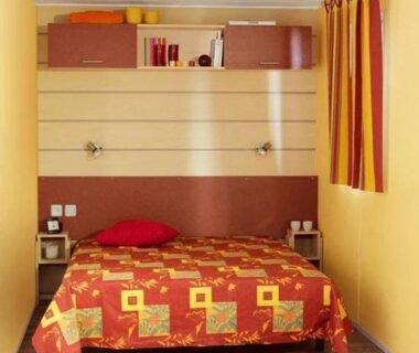 Chambre avec lit double étagères et rideau dans le ZEcamping 3 étoiles club enfant équitation piscine chauffée