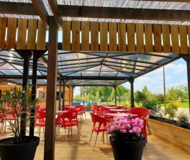 Terrasse couverte avec chaises rouges et pots au ZEcamping 3 étoiles dog friendly bien-être piscine au bord dun lac