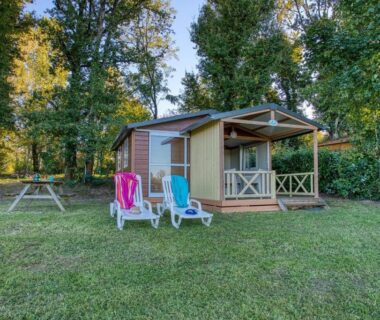 Pelouse avec mobil-home chaises longues et table de pique-nique au ZEcamping 3 étoiles